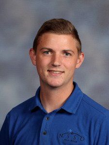 A young man in a blue shirt is smiling for a picture.