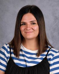 A woman in a purple shirt is smiling for the camera.
