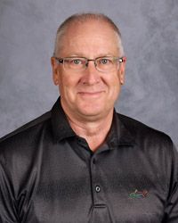 A man wearing glasses and a polo shirt is smiling for the camera.