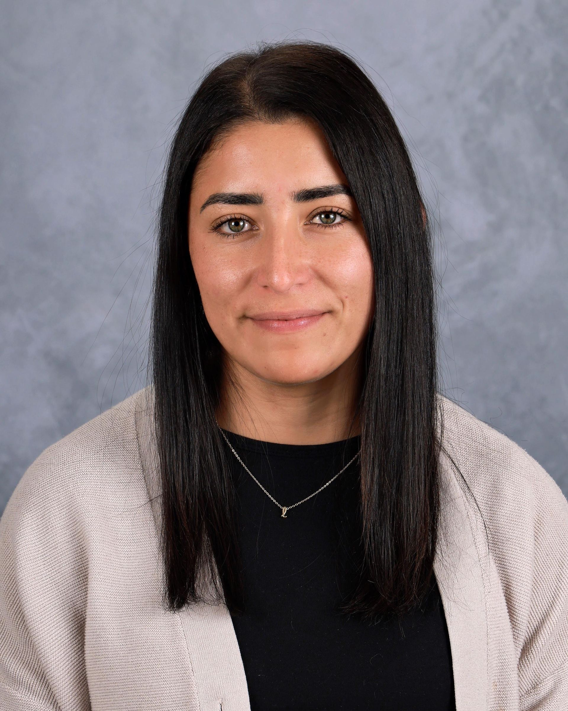 Lady long dark hair in a pink sweater and black shirt smiling at the camera