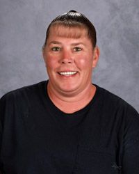 A woman in a pink t-shirt is smiling for the camera.