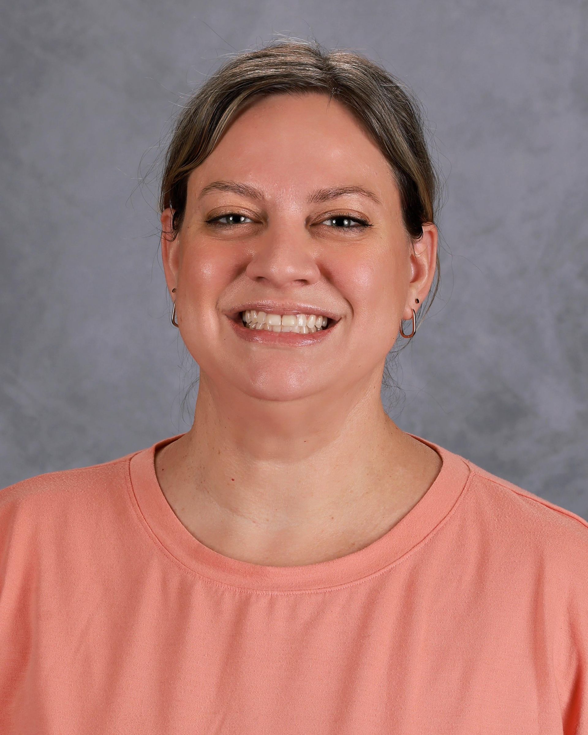 Lady in salmon colored shirt smiling at the camera