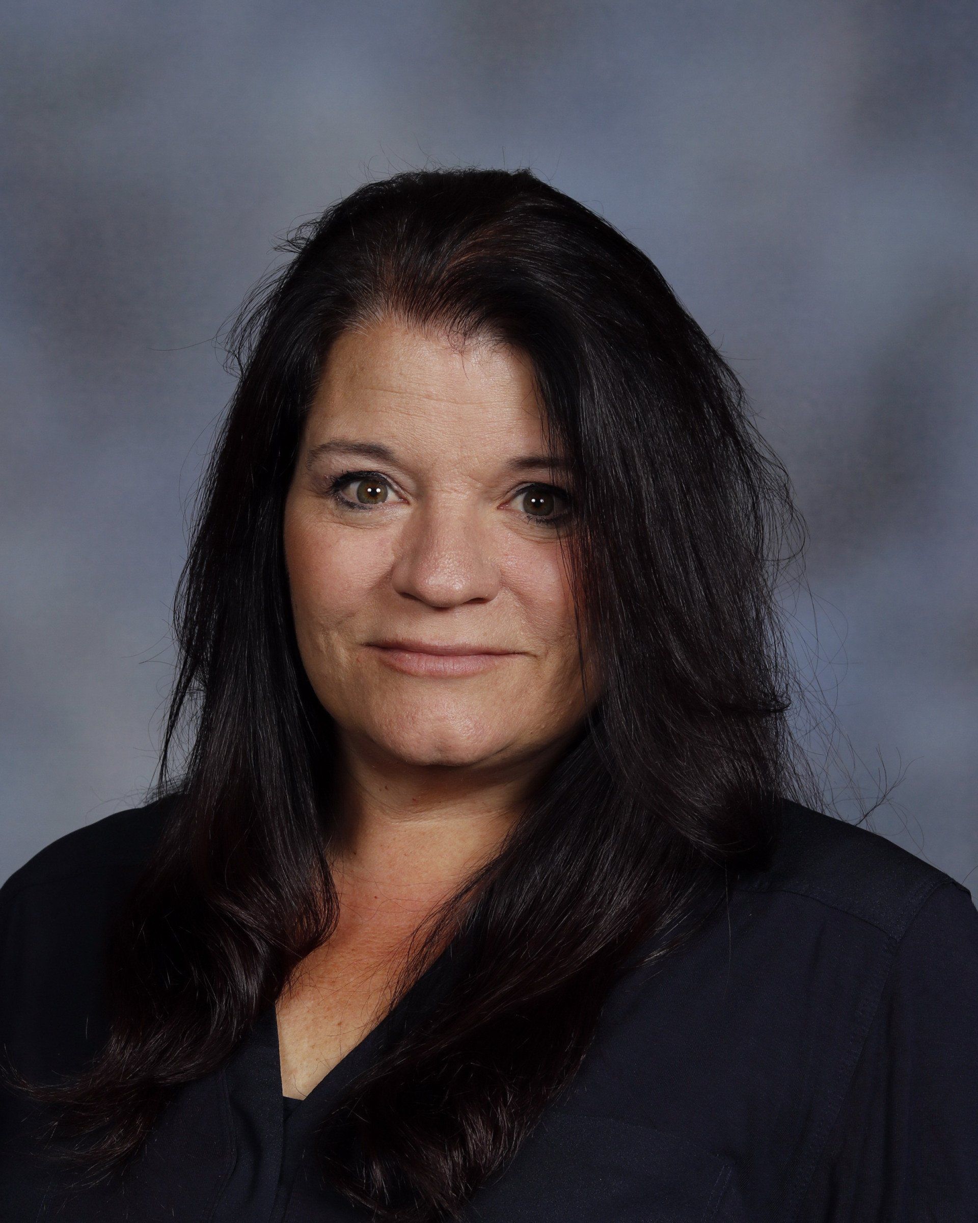 A woman with long dark hair is posing for a picture.
