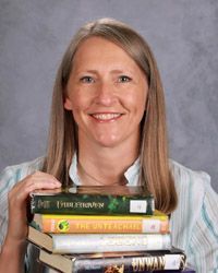 A woman is holding a bunch of books in her hands.