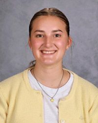 A young woman with long black hair wearing a black shirt is smiling for the camera.