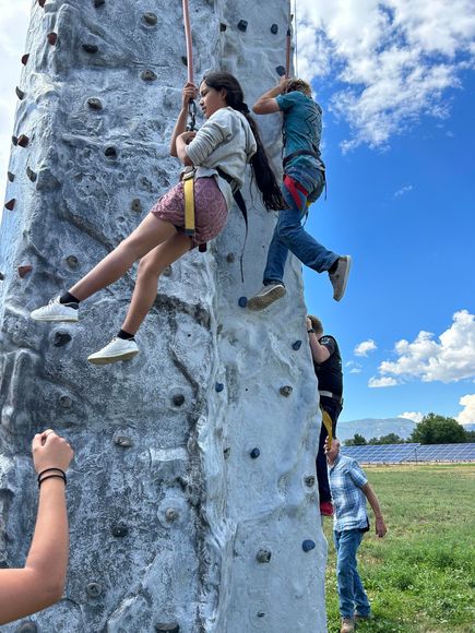 a group of children are climbing a large rock wall .