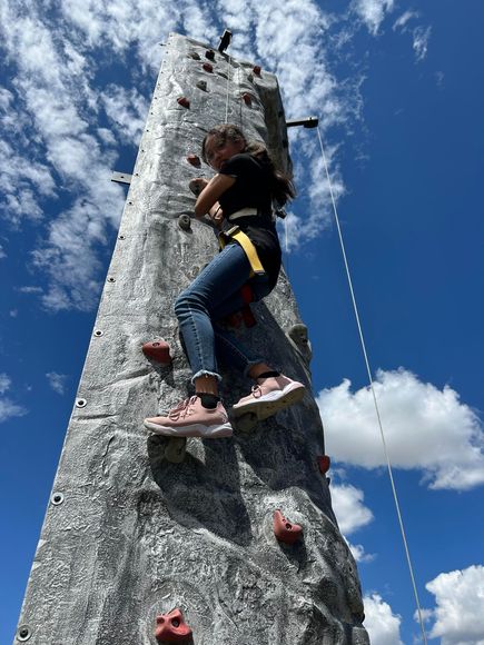 a girl is climbing a rock wall on a sunny day .