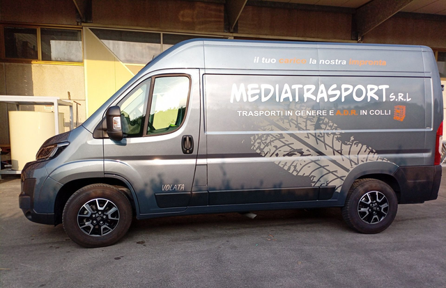 Furgone grigio Mediatrasport con logo aziendale parcheggiato all'esterno; grafica naturalistica sul lato.