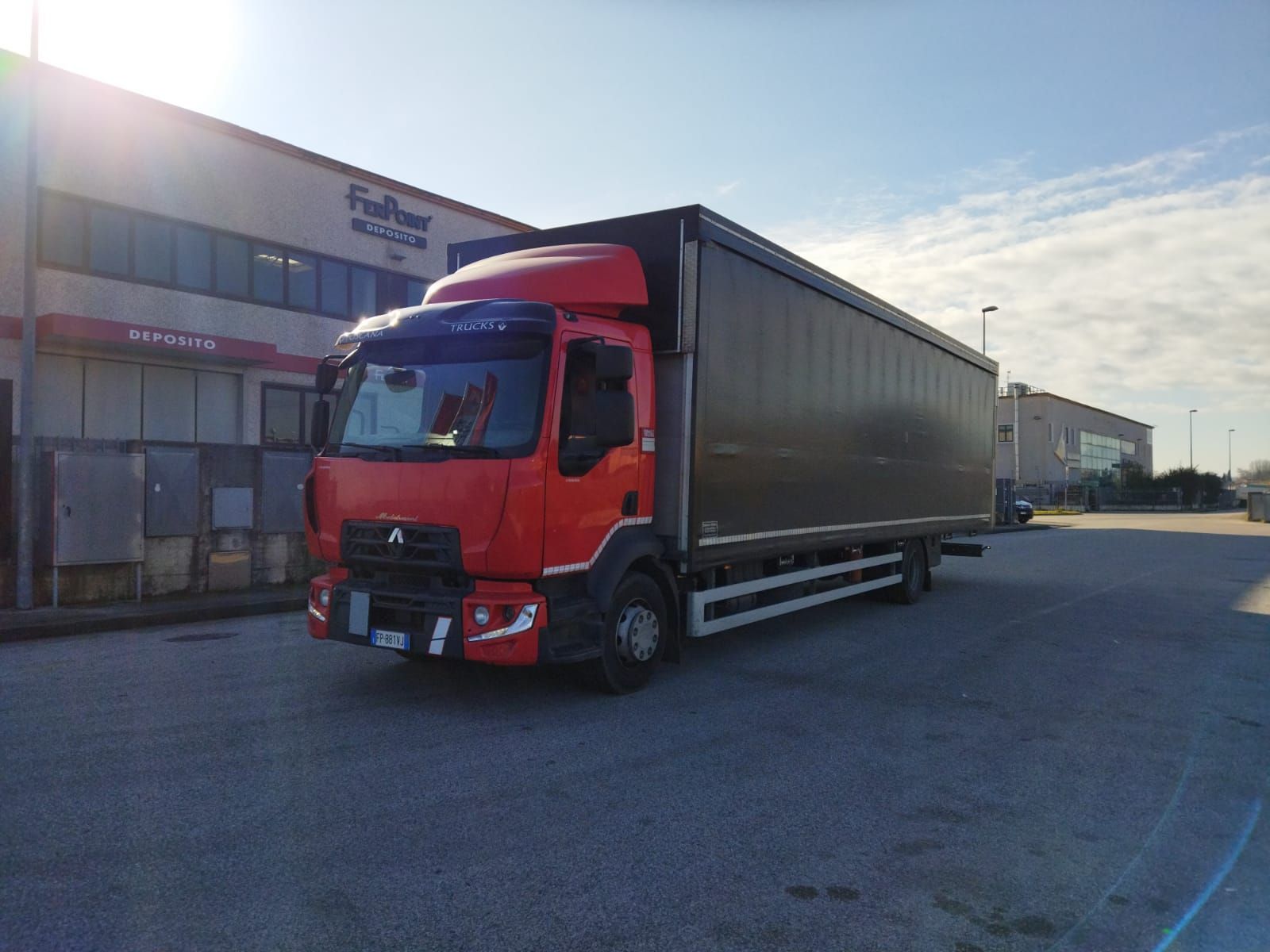 Un camioncino rosso e nero parcheggiato davanti a un edificio in una giornata di sole.
