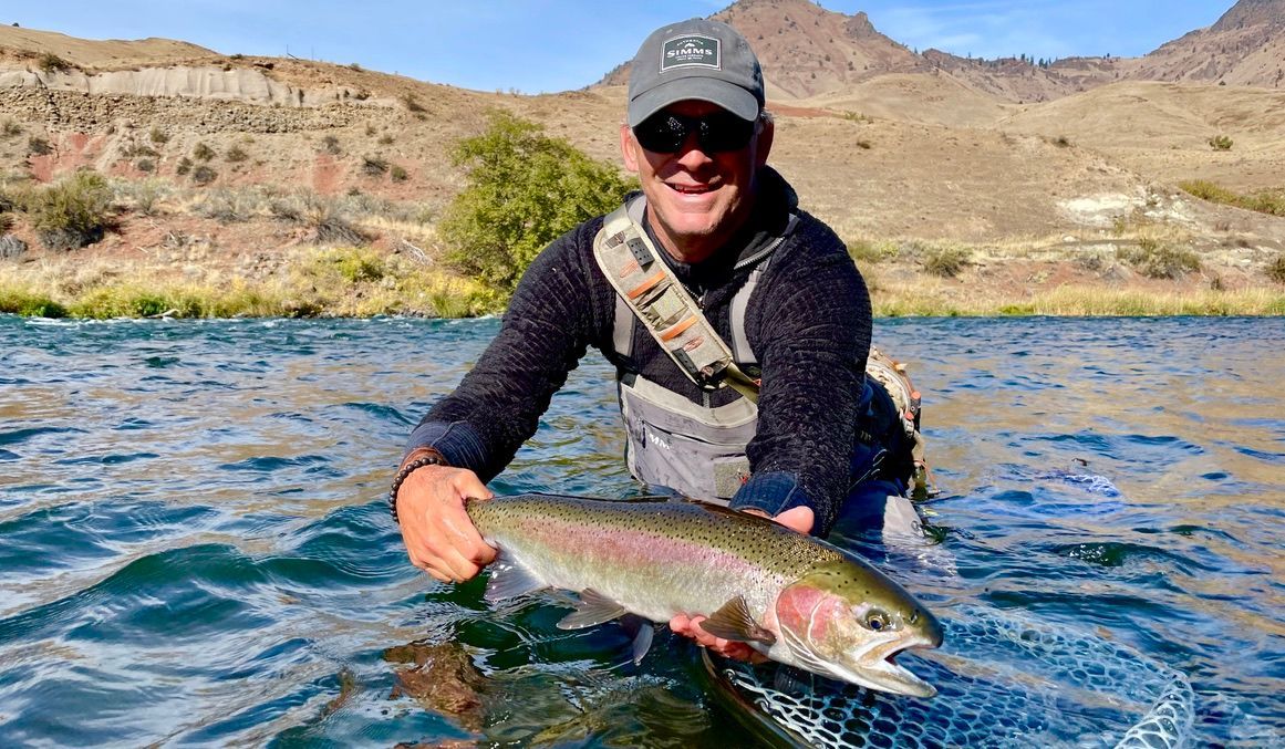 A man is holding a large fish in a river.