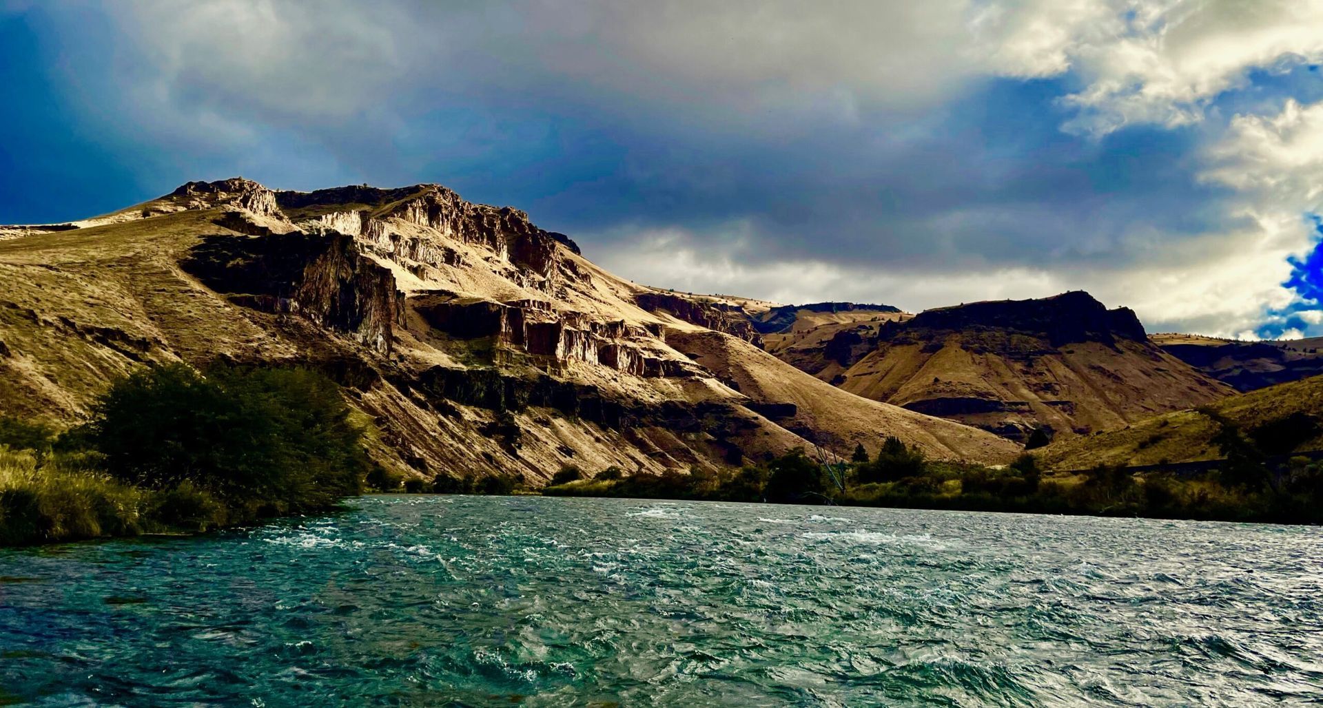 A river flowing through a valley with mountains in the background.