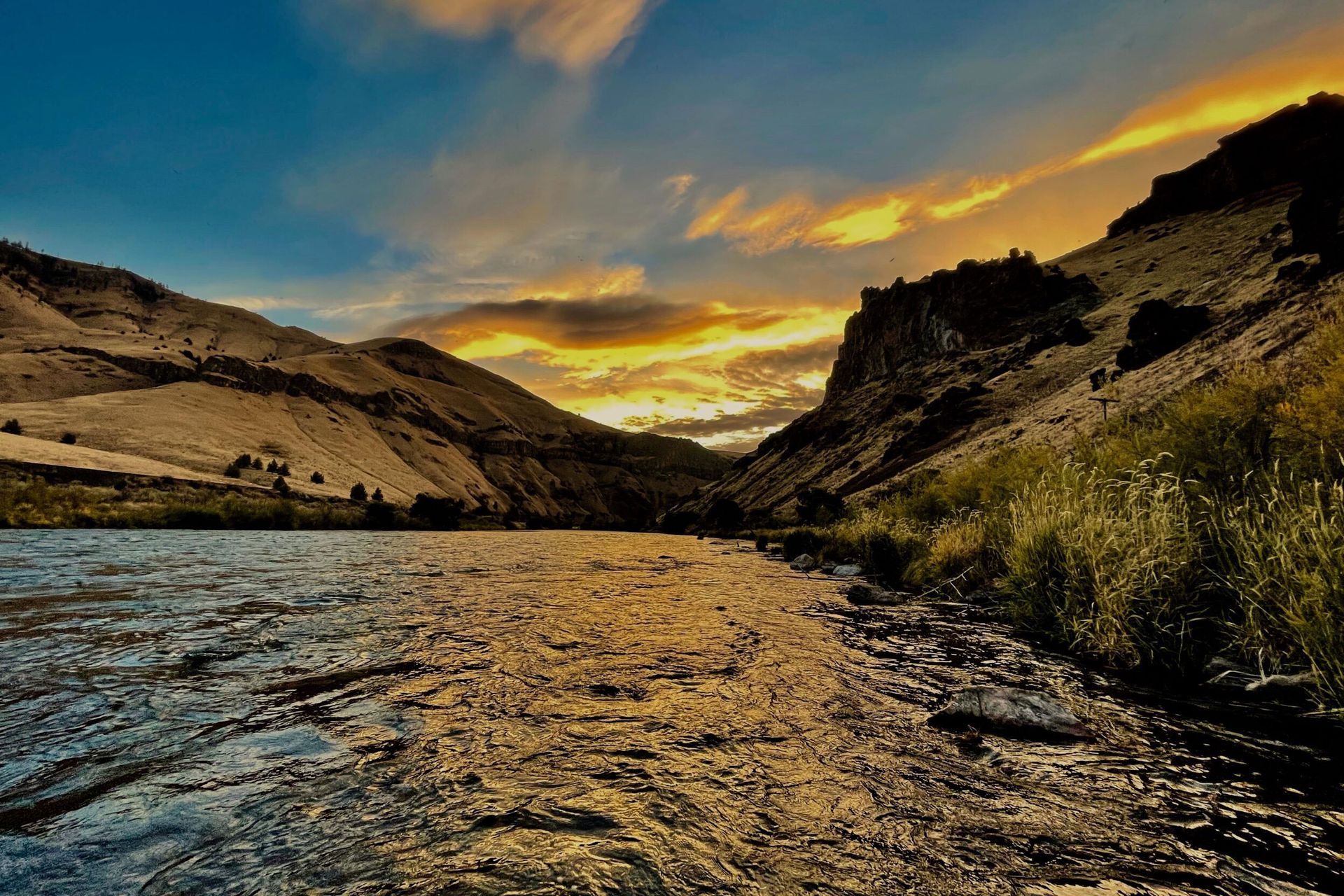 A river flowing through a canyon with mountains in the background at sunset.