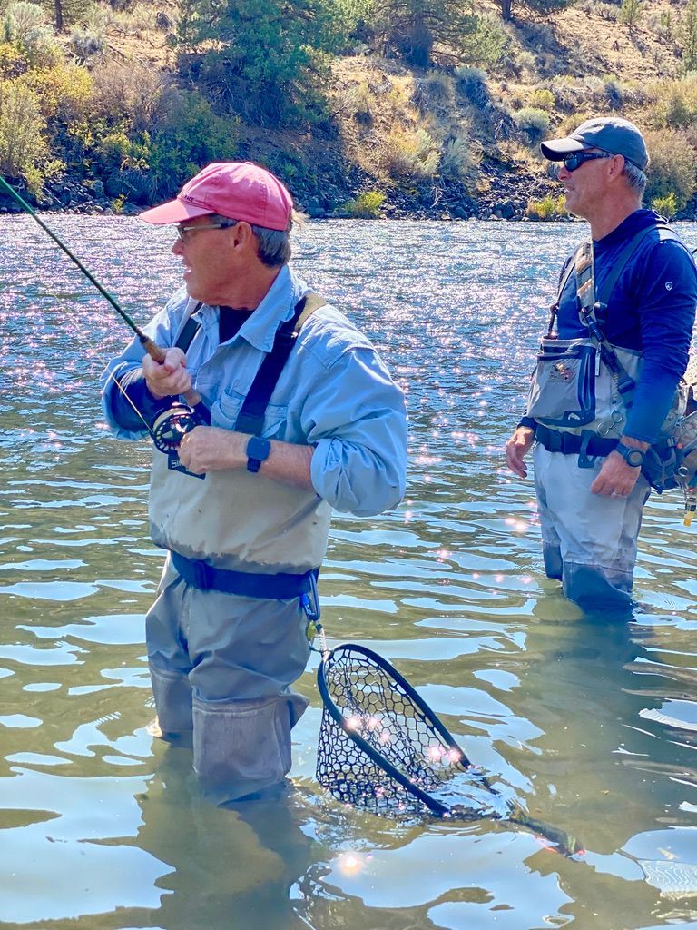 Two men are fishing in a river with a net.