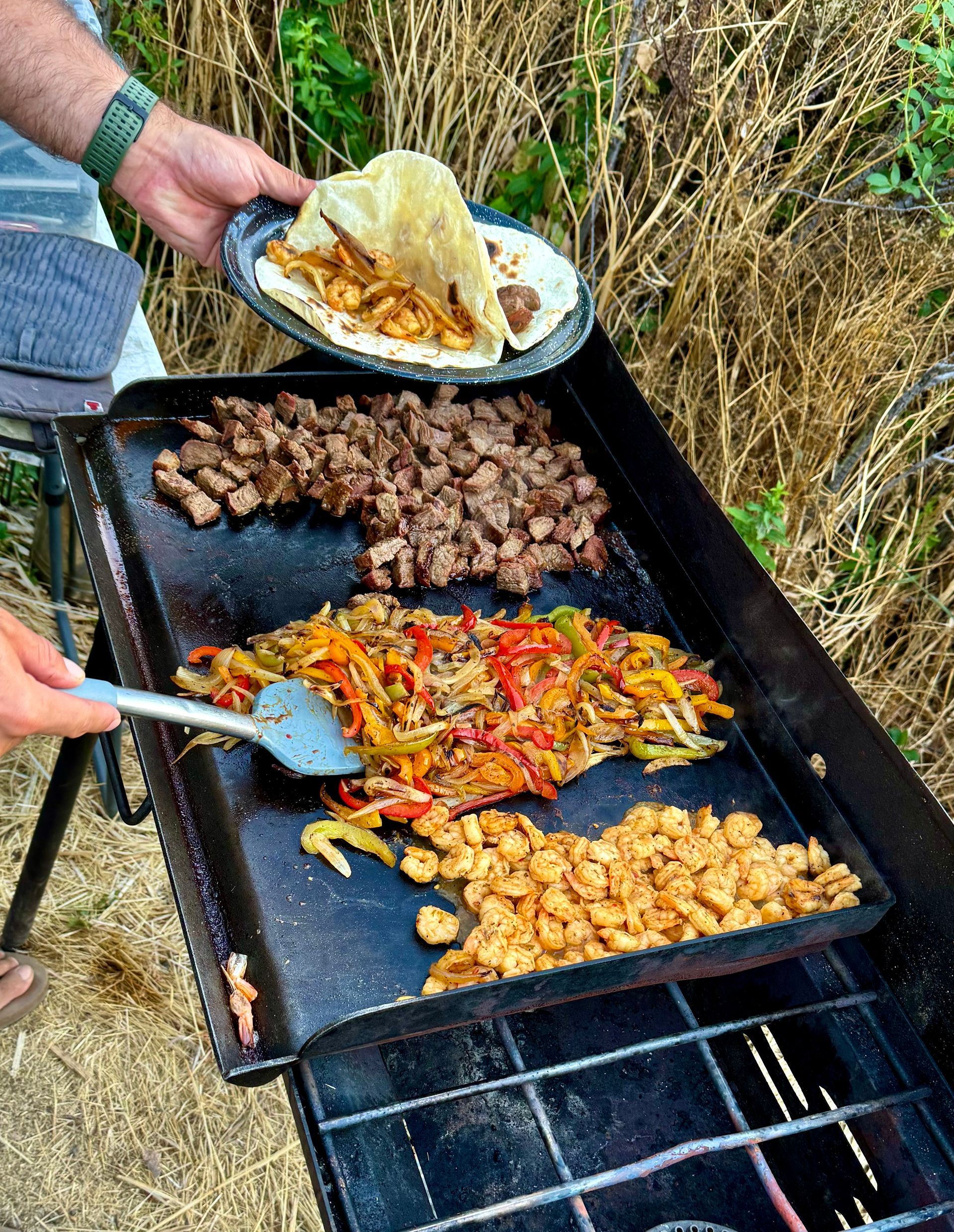 A person is cooking food on a grill outside.