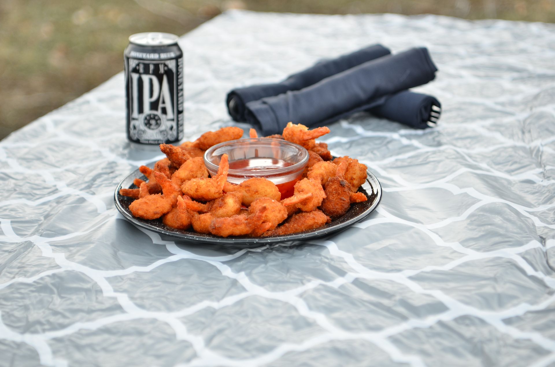 A plate of shrimp and a can of ipa beer on a table.