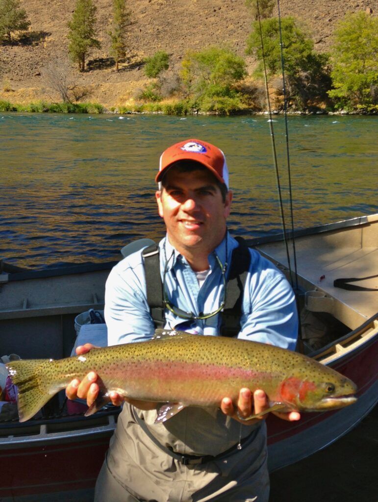 A man is holding a large fish in front of a boat.