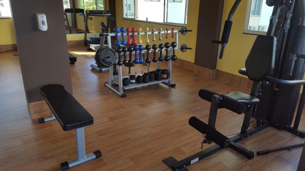 Uma academia com muitos equipamentos de exercícios e um banco.