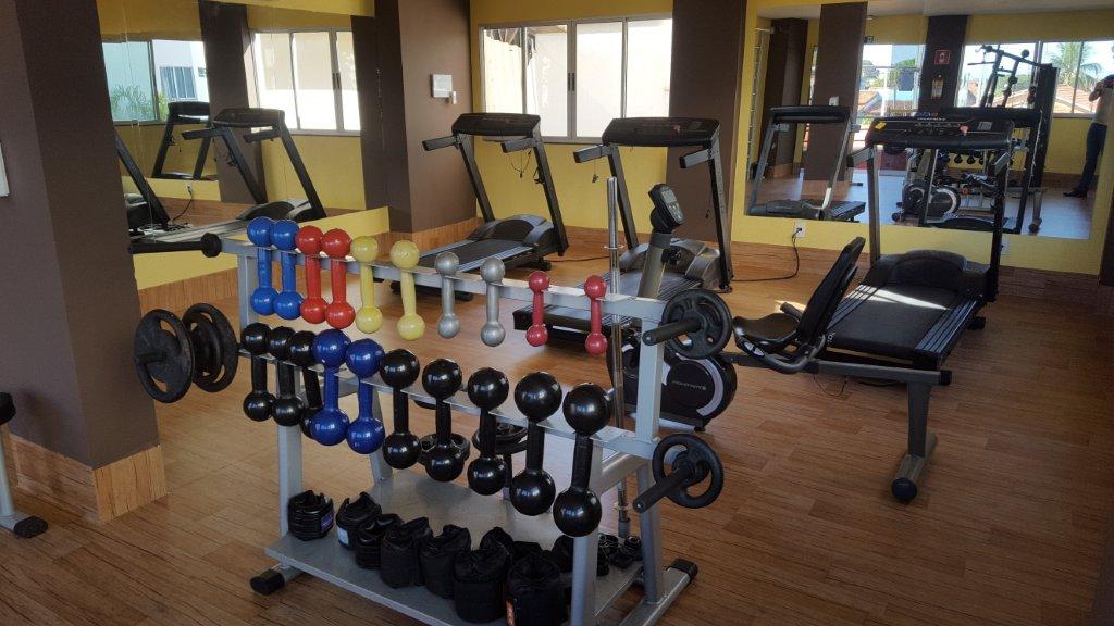 Uma academia com muitos halteres e esteiras