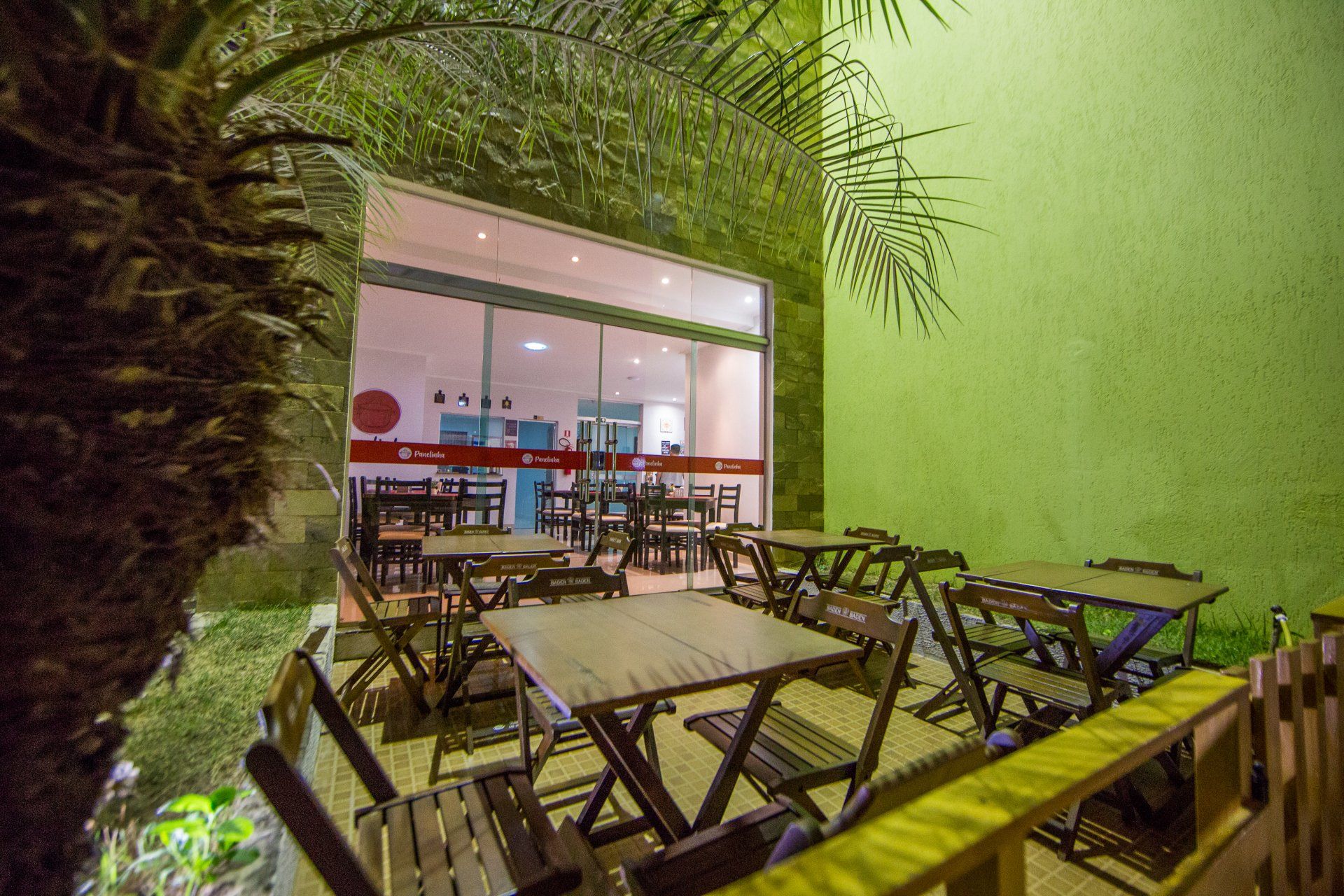 Um pátio com mesas e cadeiras em frente a um prédio à noite.