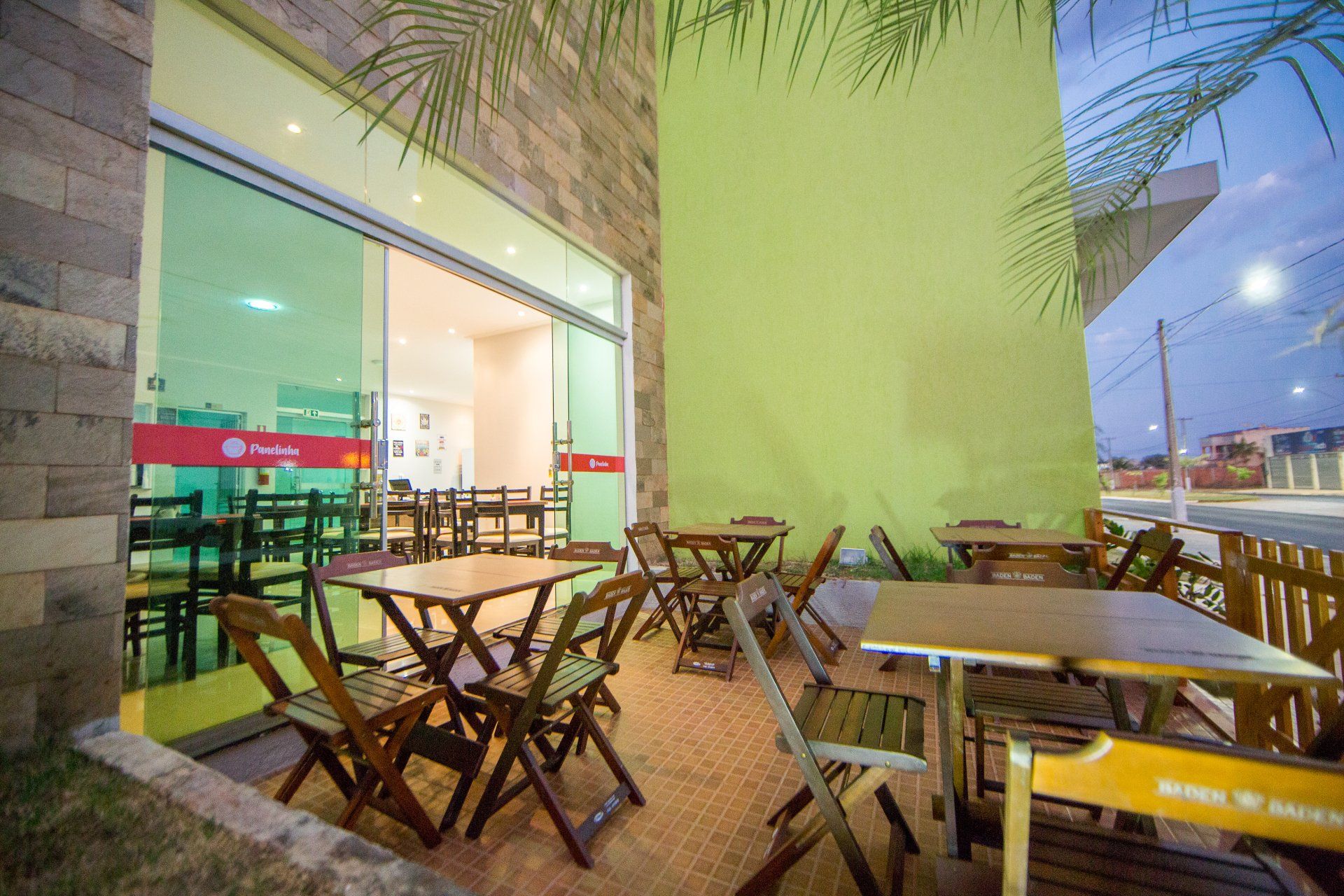 Um restaurante com mesas e cadeiras em frente a uma parede verde