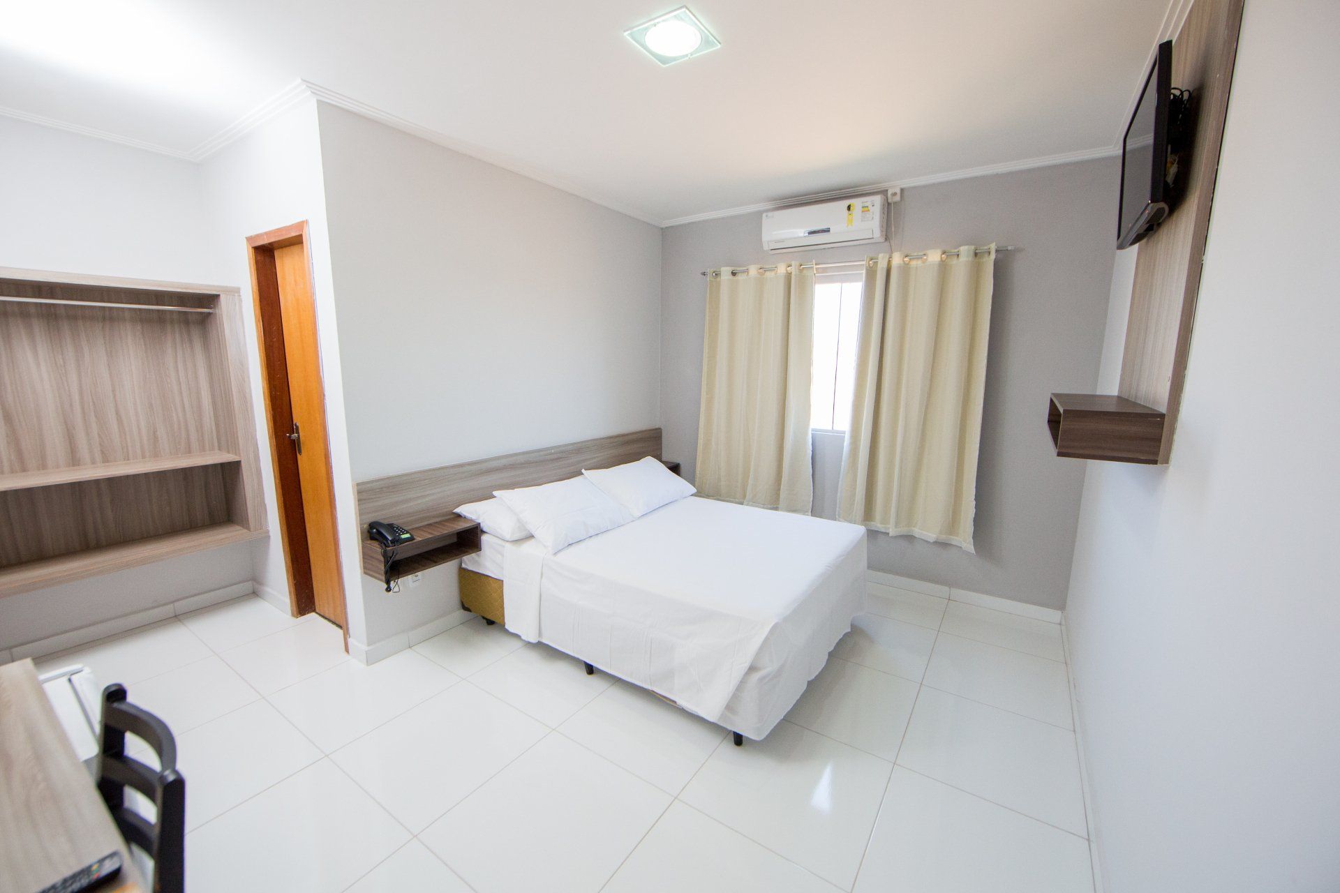 Um quarto de hotel com cama, escrivaninha e televisão.