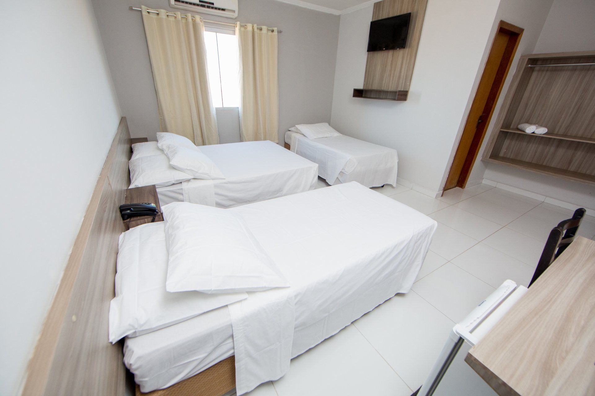 Um quarto de hotel com três camas e uma escrivaninha