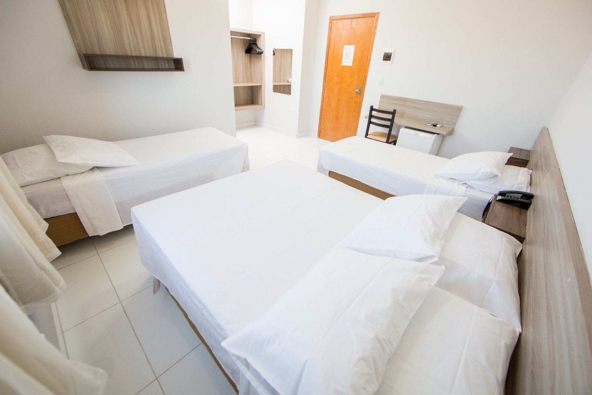 Um quarto de hotel com três camas e uma escrivaninha.