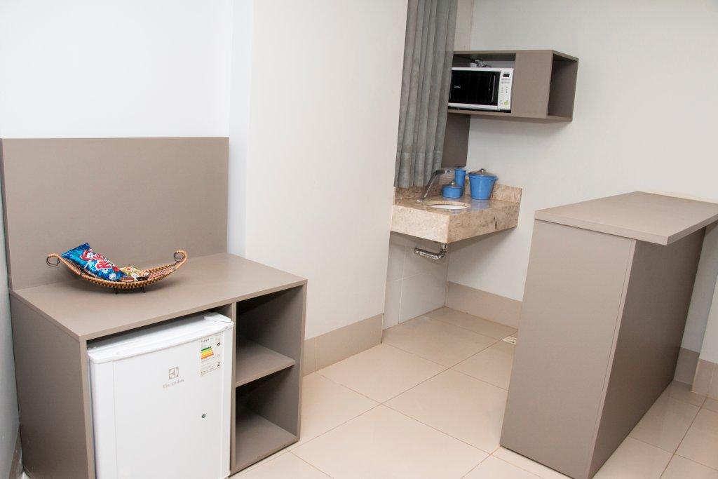 Um quarto de hotel com uma pequena geladeira e um micro-ondas.