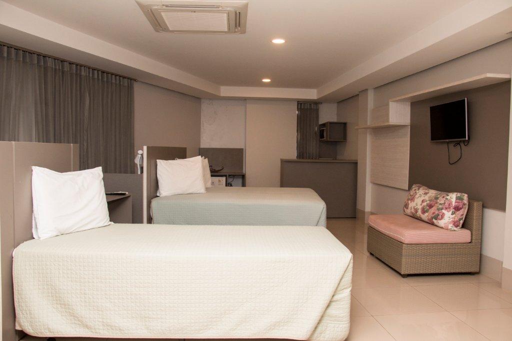 Um quarto de hotel com duas camas e um sofá.