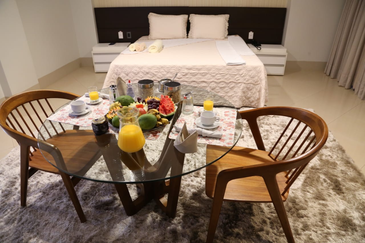 Um quarto de hotel com uma mesa e cadeiras em frente à cama.