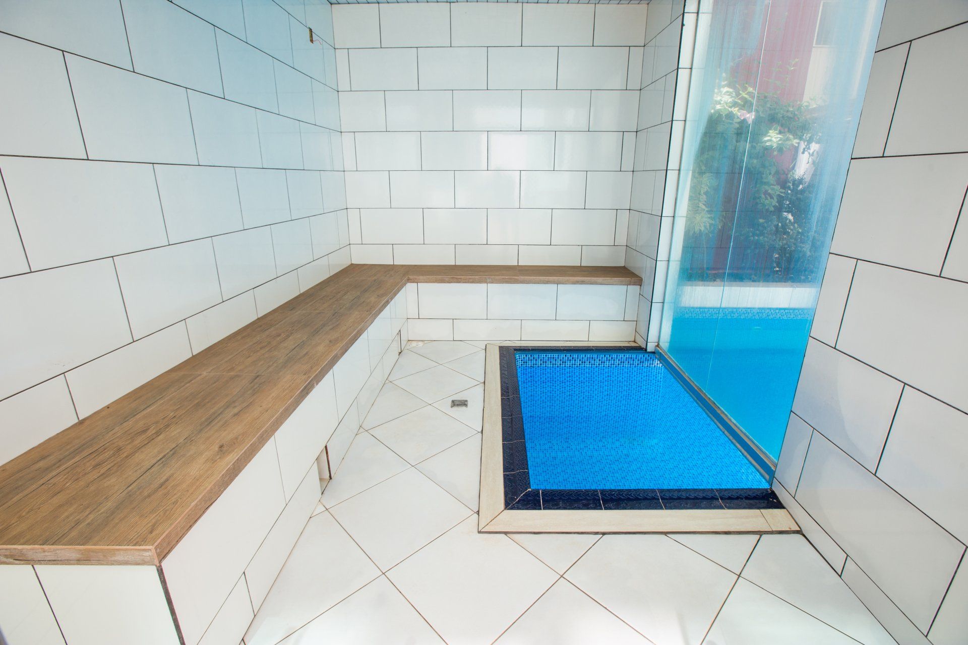 Um banheiro com azulejos brancos e uma piscina ao fundo