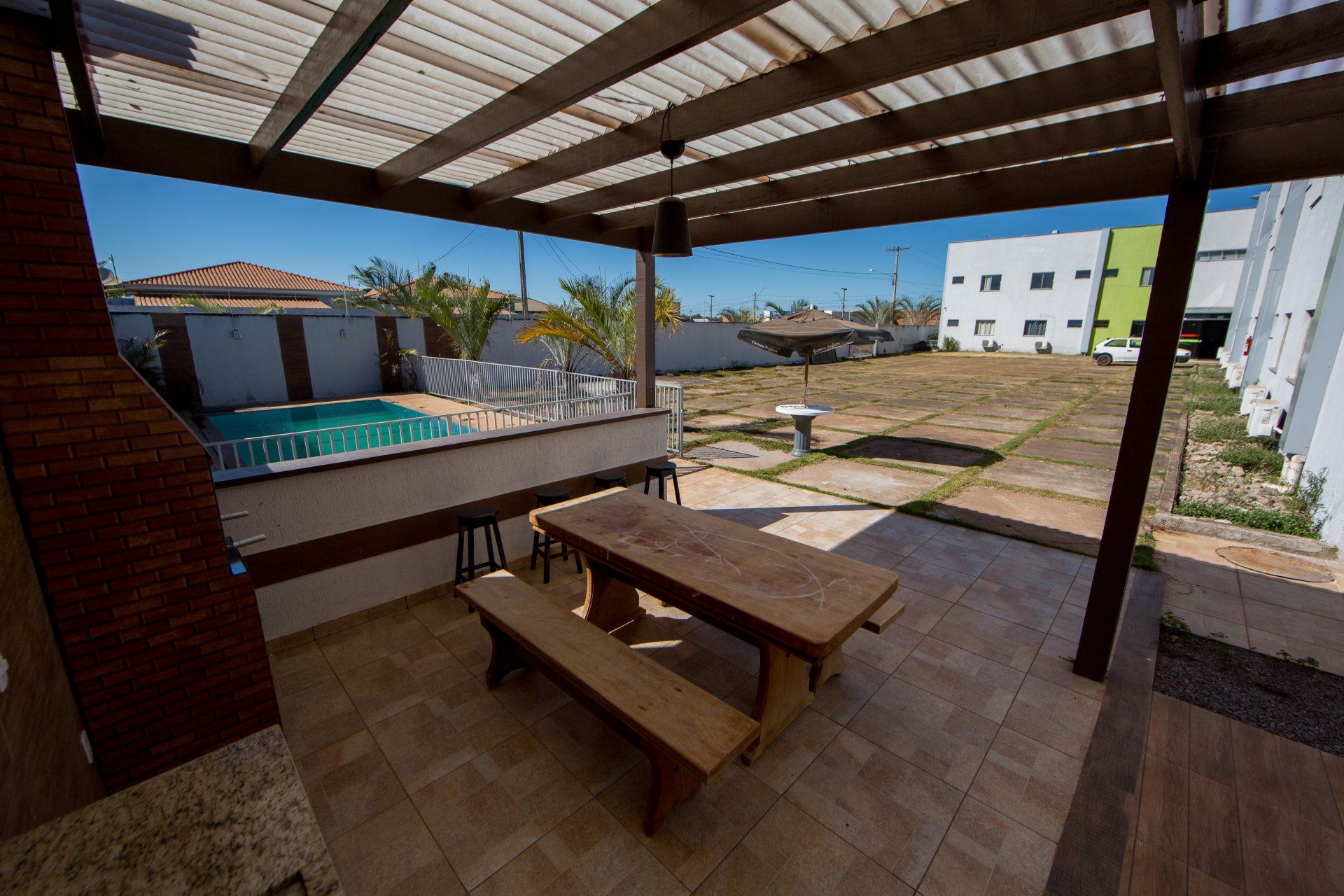 Um pátio com uma mesa e bancos sob uma pérgola