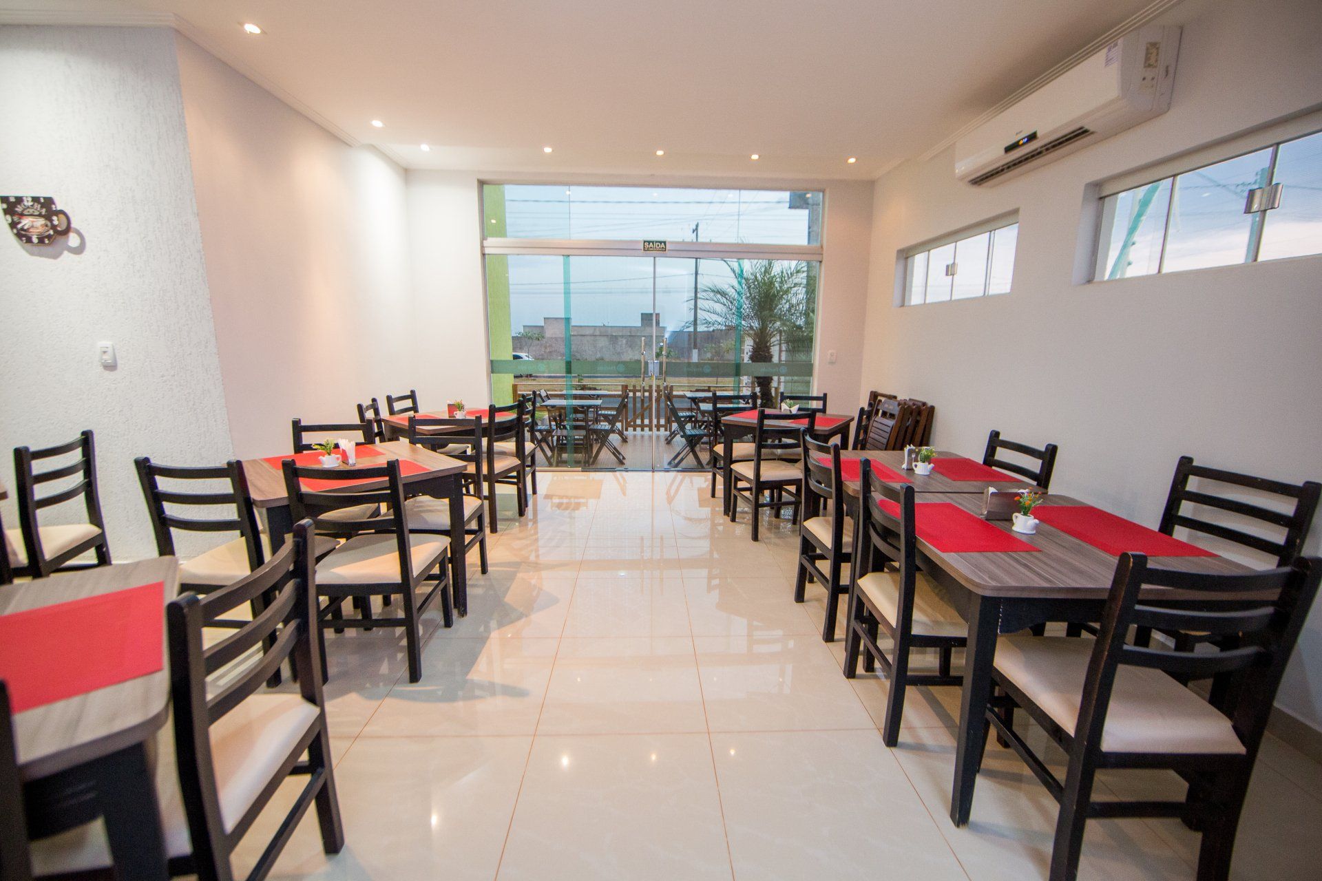 Um restaurante com mesas e cadeiras e uma grande janela.