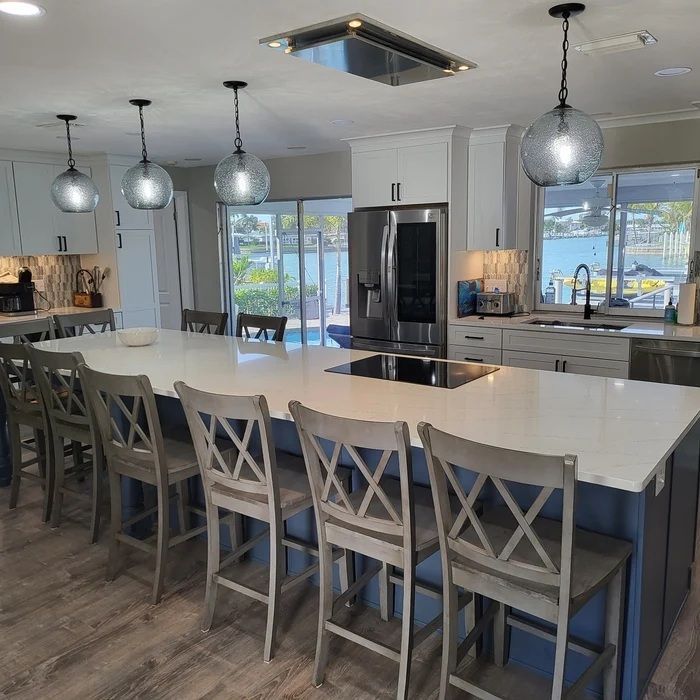 Spacious kitchen with a large island, blue and white cabinets, and pendant lights.
