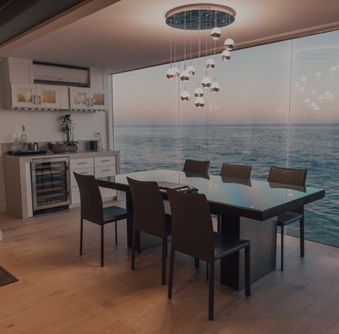 Dining room with ocean view, dark table, black chairs, and modern light fixture.