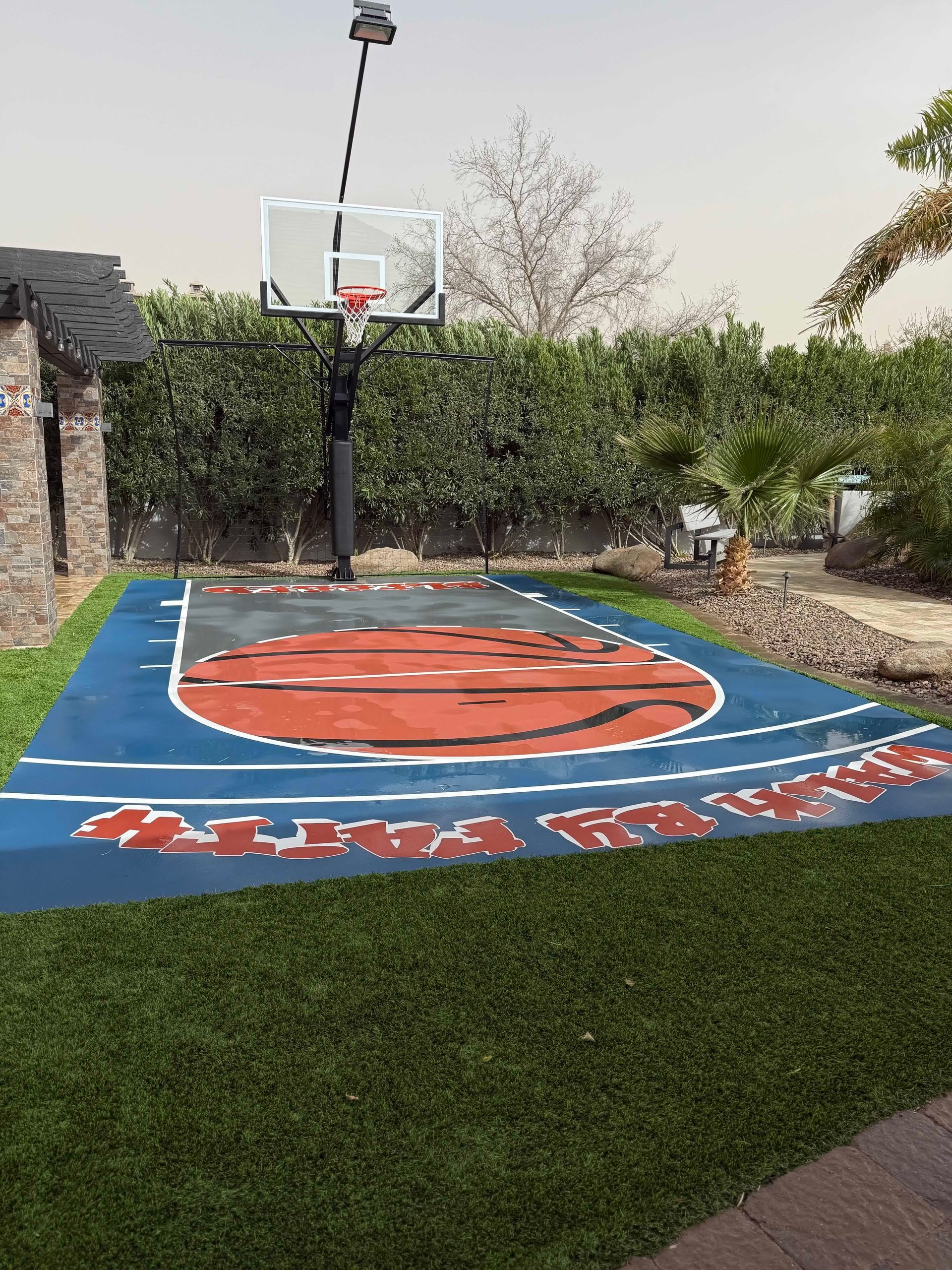 A basketball court in a backyard with a basketball hoop.