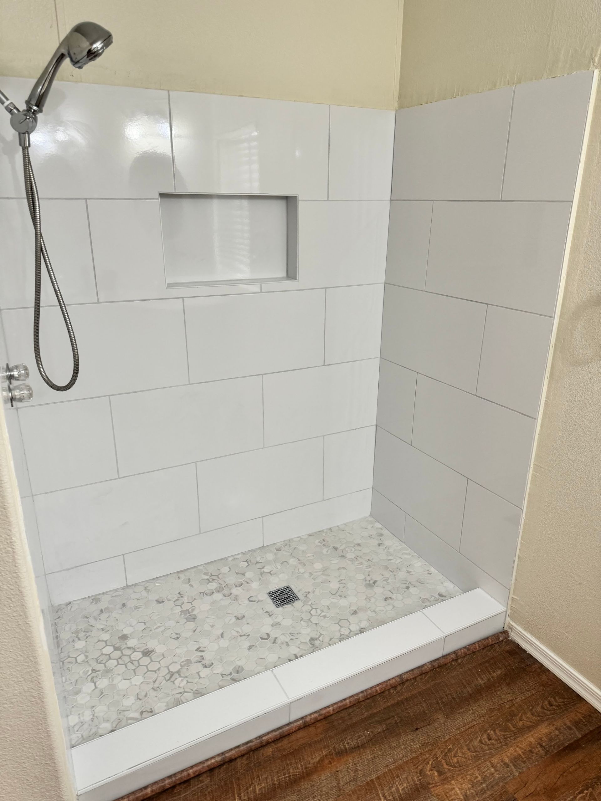 A bathroom with a walk in shower and a shower head.