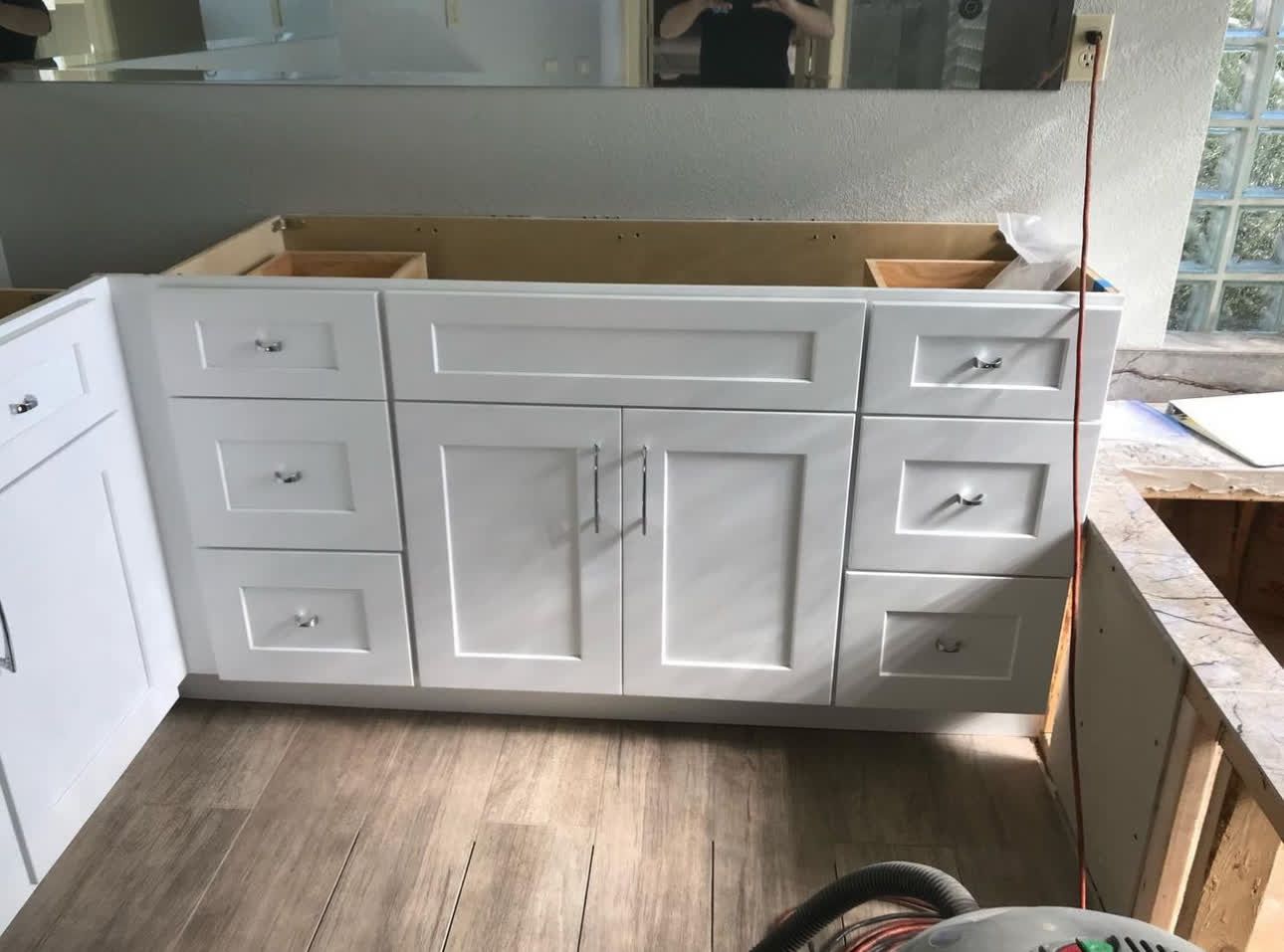 A kitchen with white cabinets and drawers is being built.