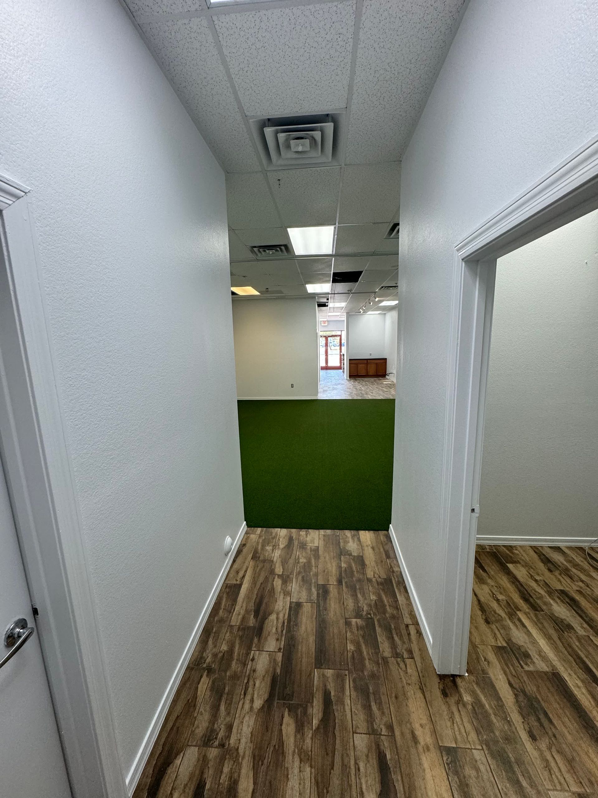 A hallway in a building with wooden floors and white walls.