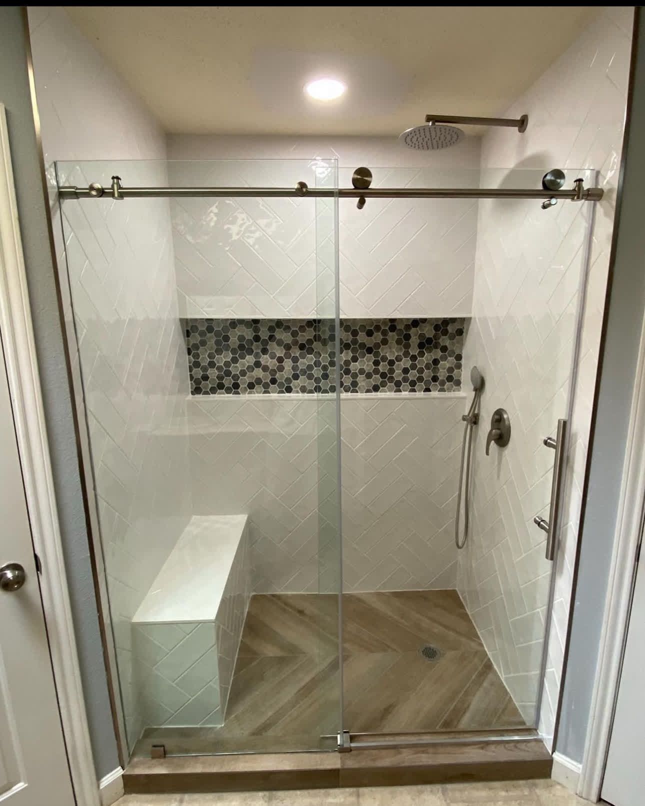 A bathroom with a sliding glass shower door and a bench.