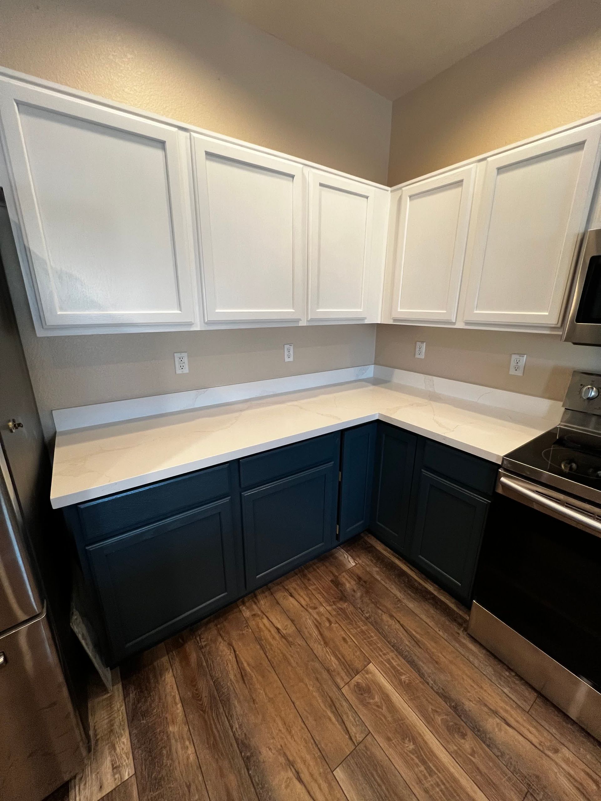 A kitchen with blue cabinets , white counter tops , and a stove.