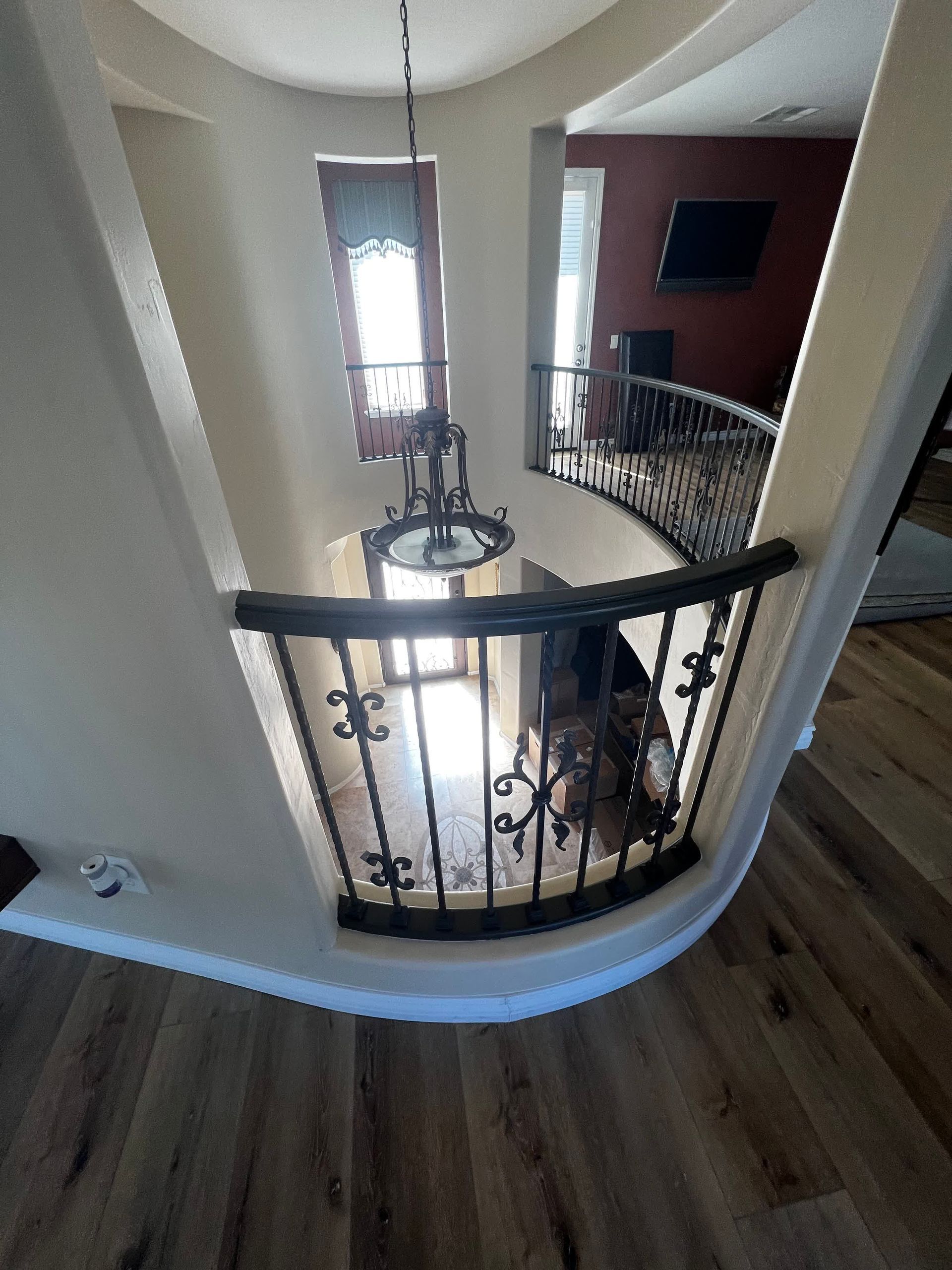 A staircase with a wrought iron railing and a chandelier hanging from the ceiling.