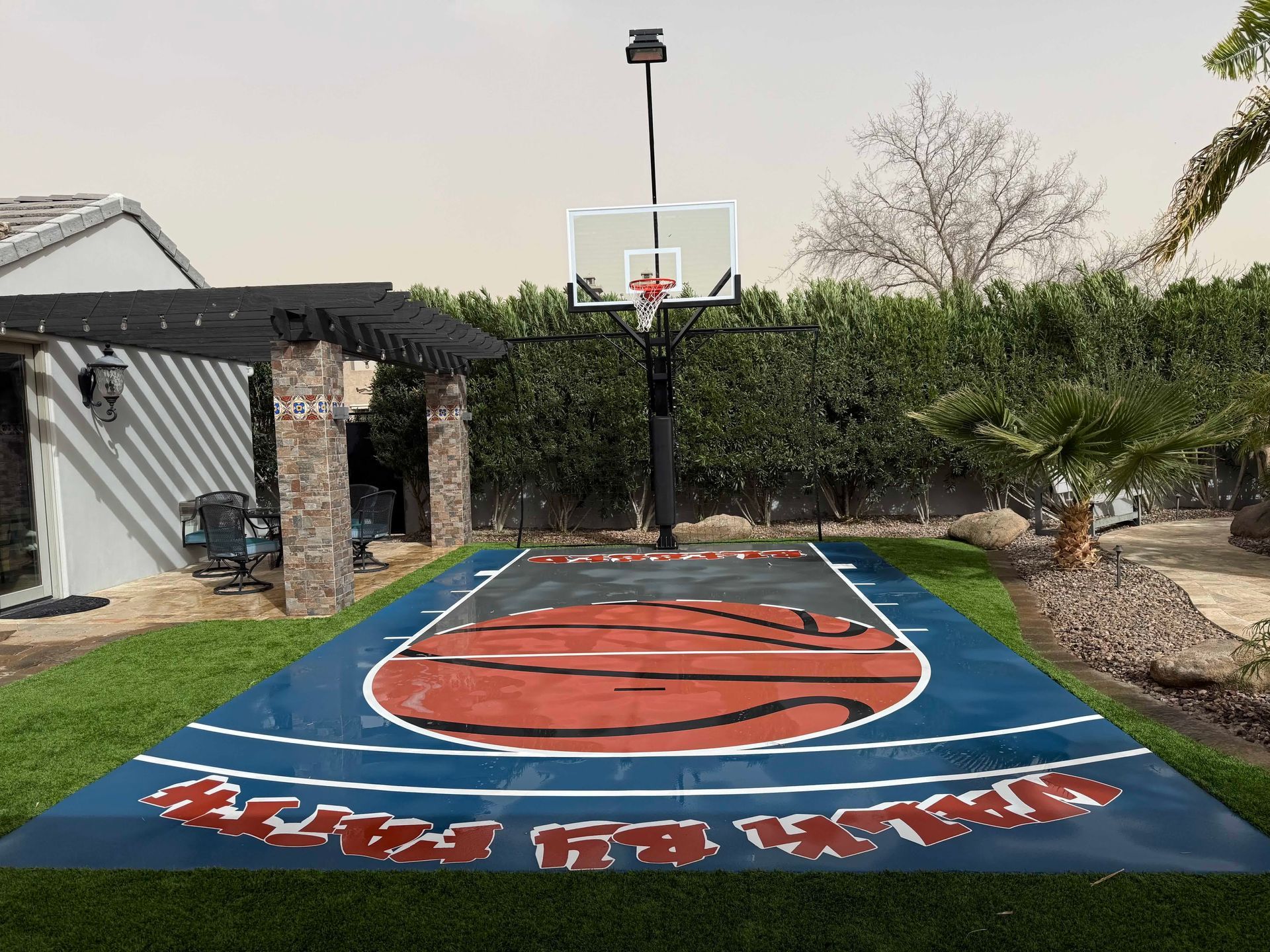 There is a basketball court in the backyard of a house.