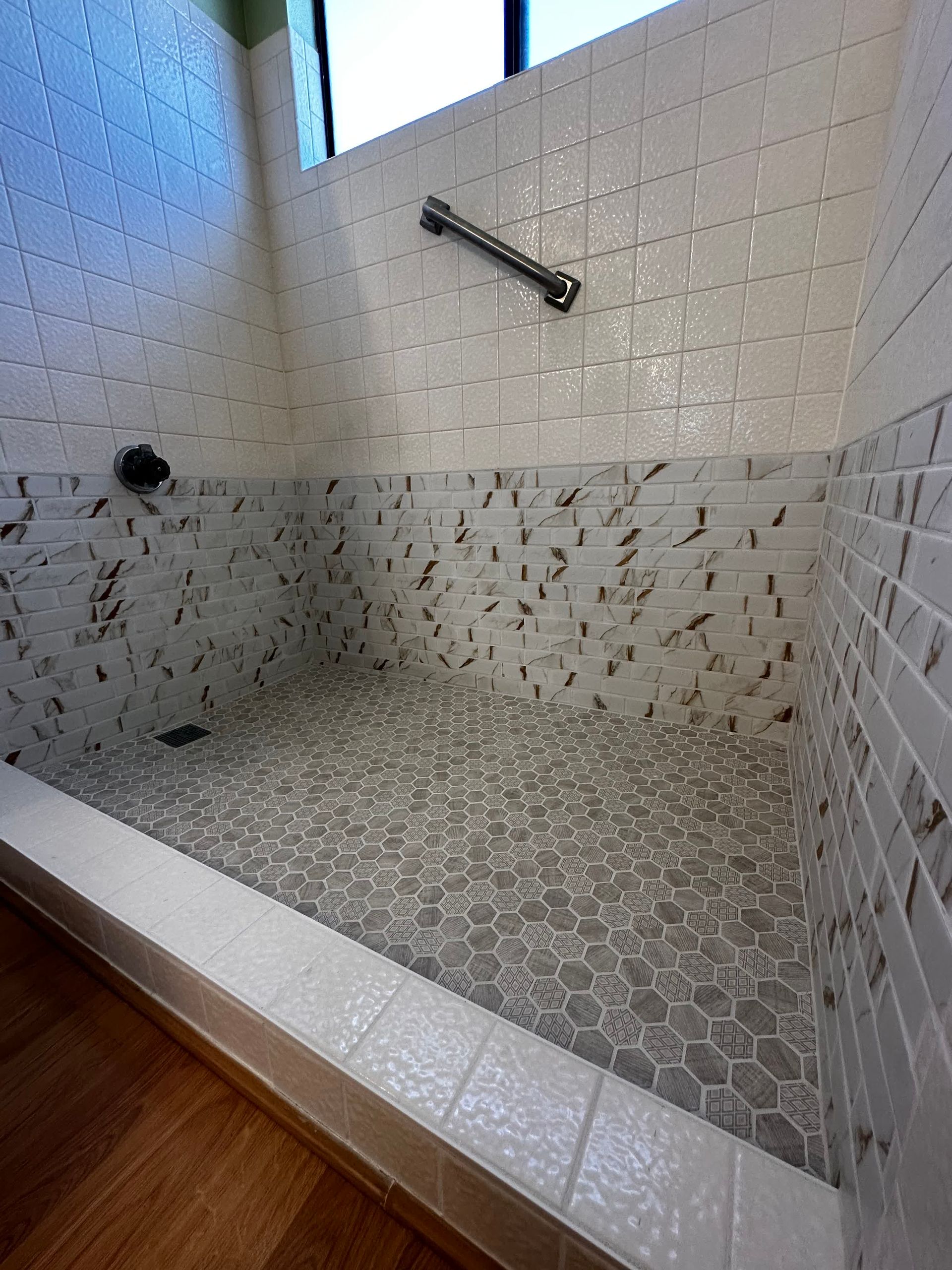 A bathroom with a walk in shower and a window.