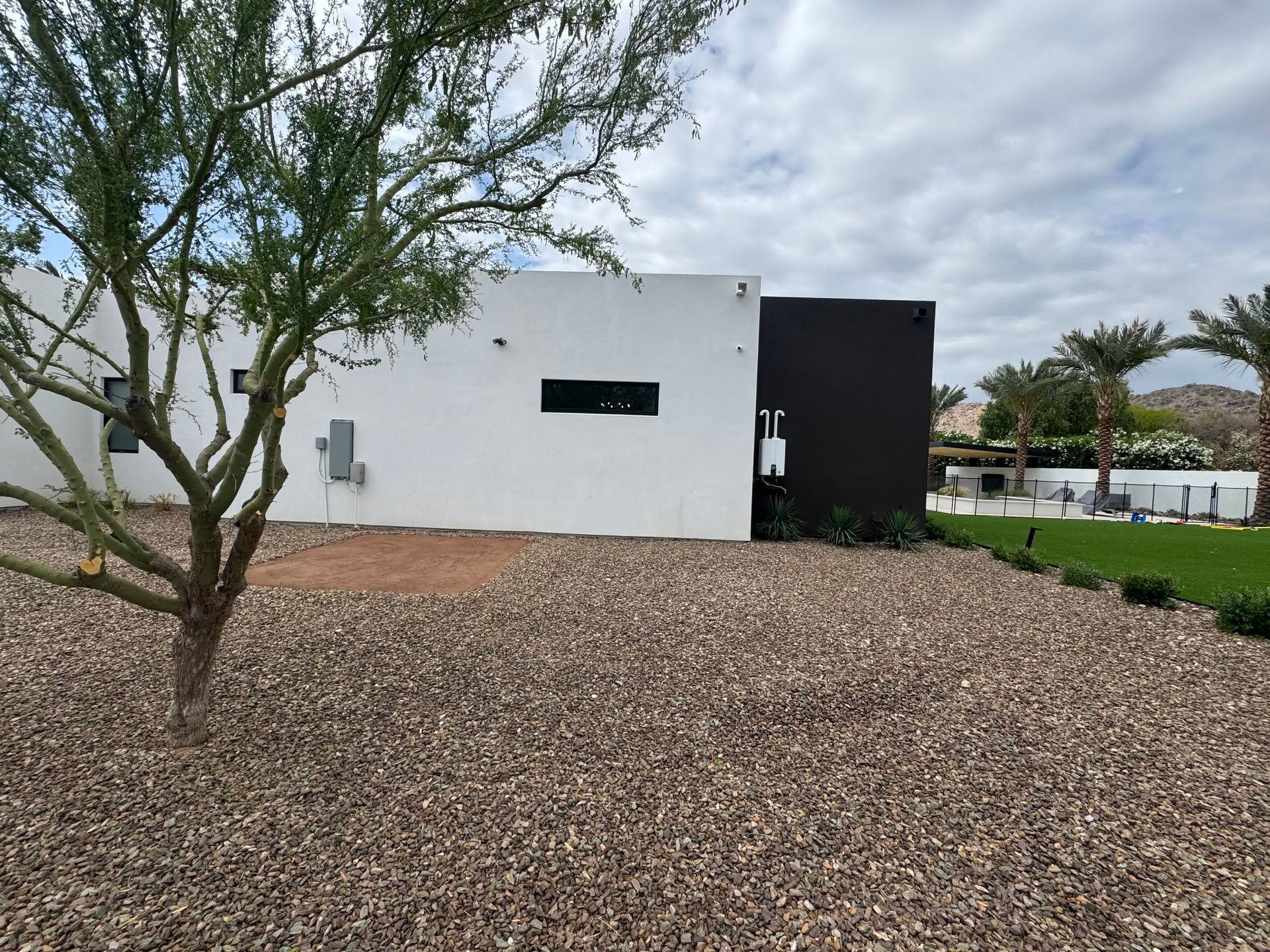 A white house with a black trim and a tree in front of it