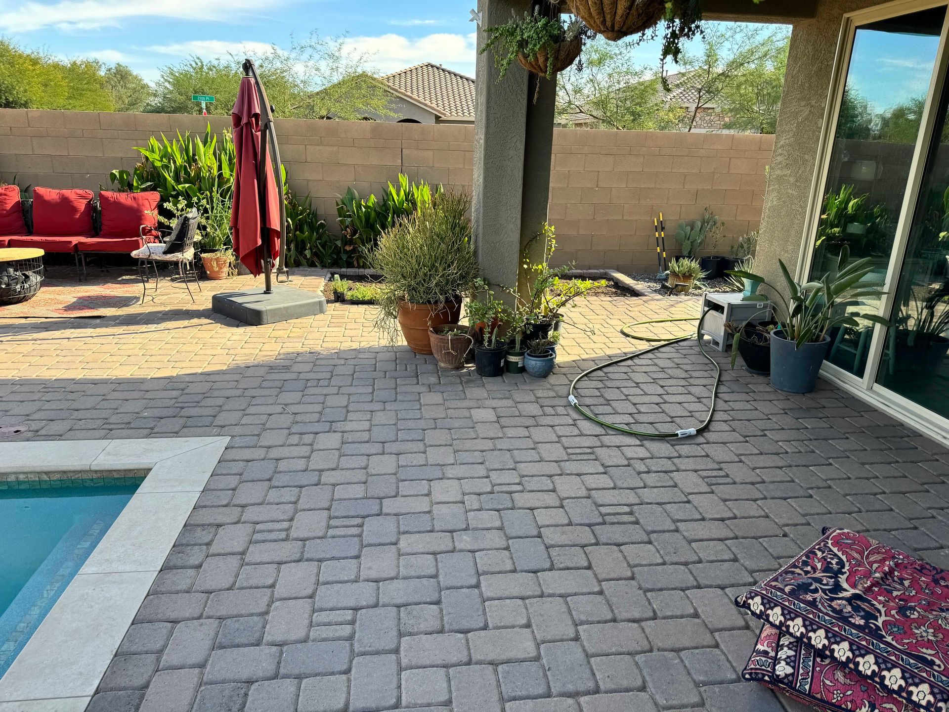 A patio with a swimming pool and a red umbrella.
