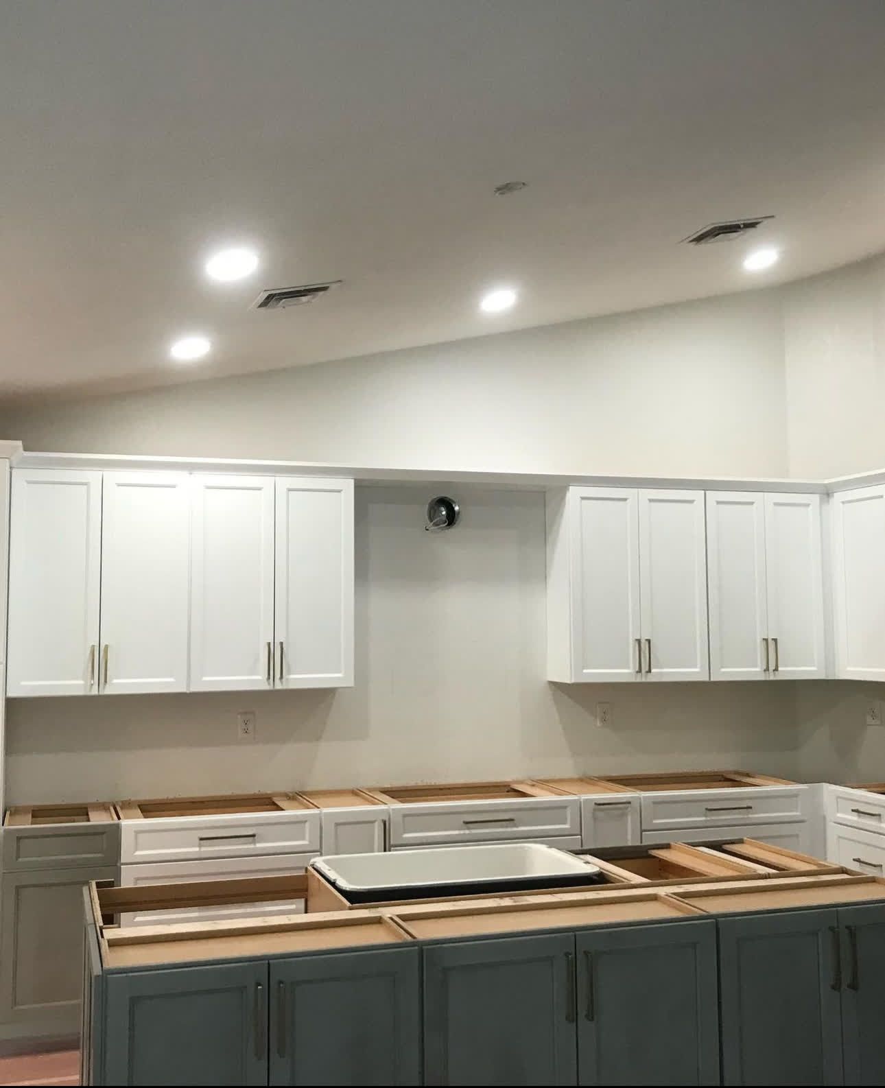 A kitchen with white cabinets and blue cabinets is being remodeled.