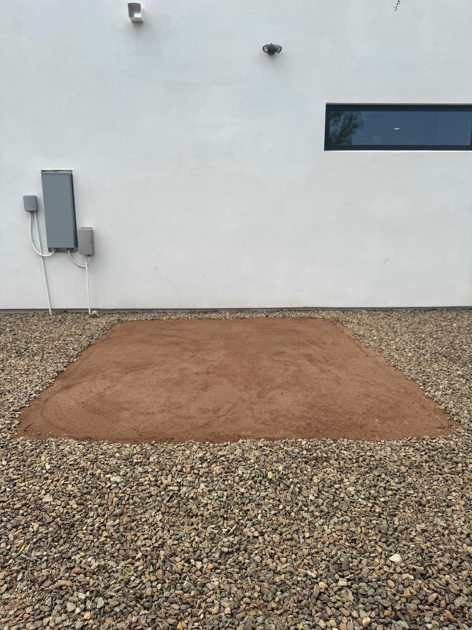 A large pile of gravel is in front of a white building.