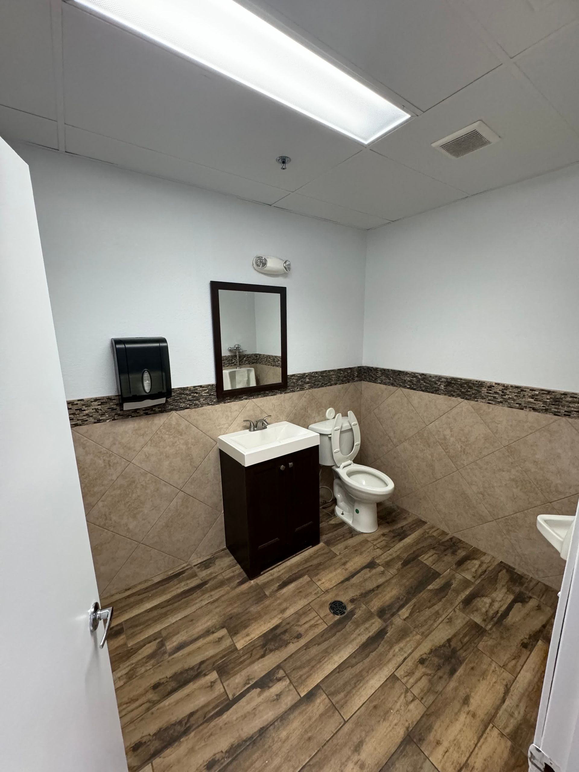 A bathroom with a toilet , sink and mirror.