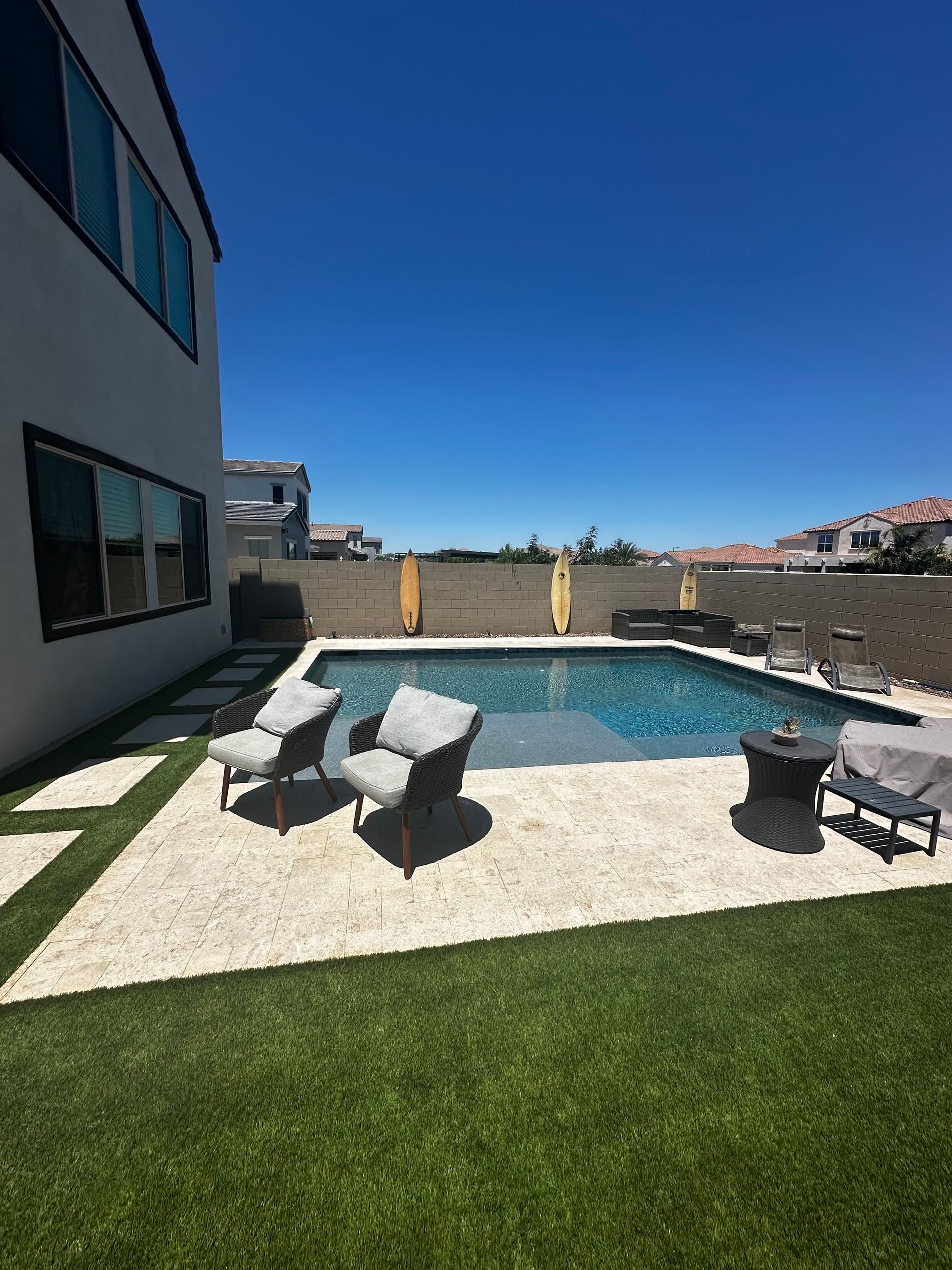 There is a large swimming pool in the backyard of a house.